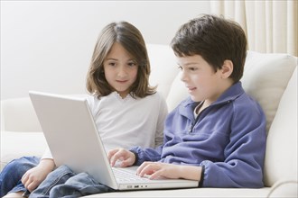 Hispanic brother and sister using laptop