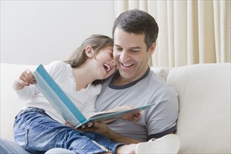 Hispanic father reading book to daughter