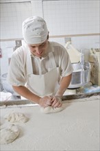 Hispanic baker kneading dough