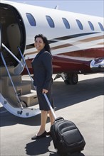 Hispanic businesswoman boarding private jet