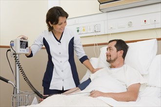 Nurse taking patient's blood pressure in hospital room