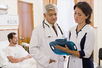 Doctor and nurse discussing patient in hospital room