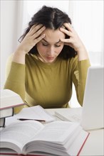 Mixed race woman with headache studying textbooks