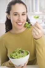 Mixed race woman eating salad