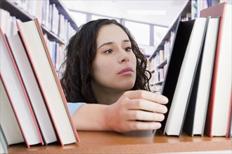 Mixed race woman looking for book in library
