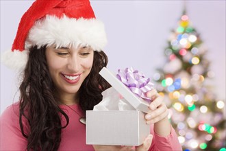 Mixed race woman opening Christmas gift