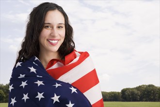 Mixed race woman wrapped in American flag