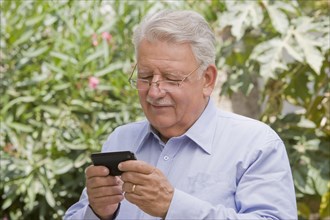 Senior Chilean man text messaging on cell phone