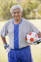Senior Chilean soccer player holding soccer ball