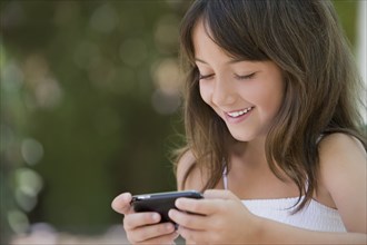 Hispanic girl text messaging on cell phone