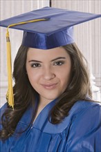 Hispanic teenage girl in graduation cap and gown
