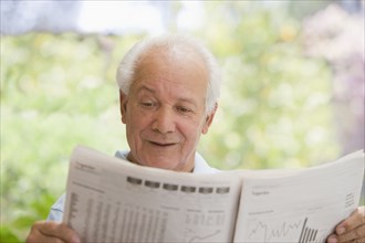 Senior Hispanic man reading financial newspaper