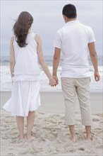 Hispanic couple holding hands on beach