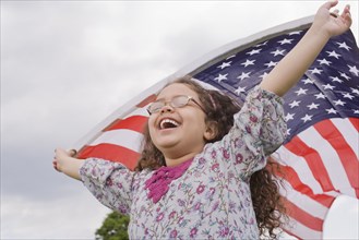 Hispanic girl holding American flag with arms raised