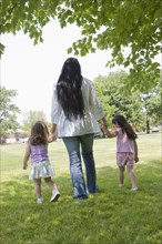 Hispanic mother walking in park with daughters