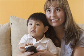 Hispanic mother and son watching television