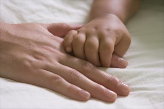 Hispanic mother and baby boy holding hands