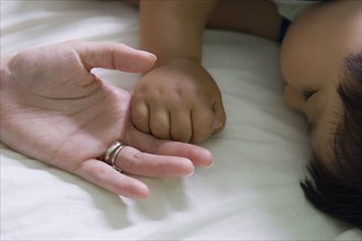 Hispanic mother and baby boy holding hands