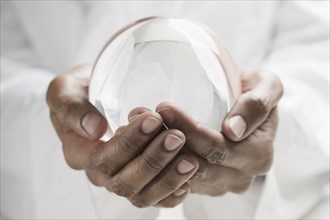 Close up of mixed race man holding crystal ball