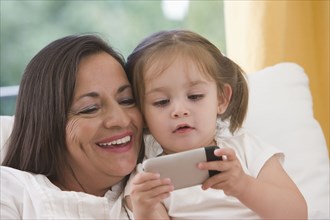 Hispanic grandmother showing cell phone to granddaughter