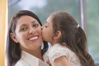 Hispanic girl kissing mother's cheek