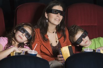 Hispanic mother and children watching 3D movie