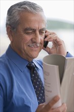 Hispanic businessman talking on cell phone and reading report