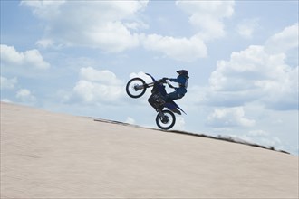 Chilean teenager riding motorcycle on sand dune