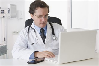 Caucasian doctor sitting at desk with laptop