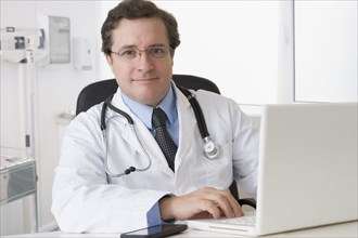 Caucasian doctor sitting at desk with laptop