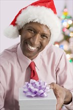 Mixed race businessman giving Christmas present