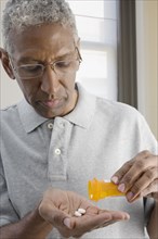 Mixed race man shaking pills from bottle