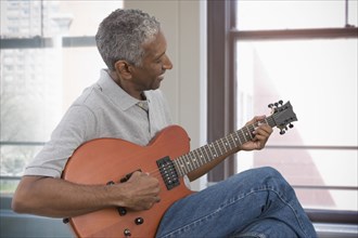 Mixed race man playing electric guitar
