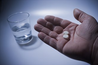Close up of pills in Hispanic man's hand