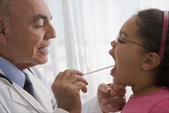 Hispanic doctor checking patient's throat