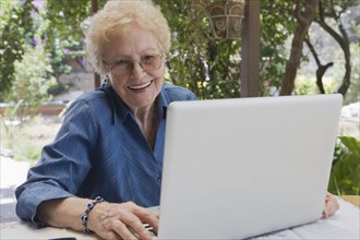 Older Hispanic woman using laptop outdoors