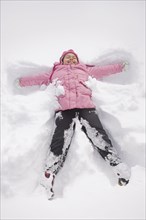 Hispanic girl making snow angel
