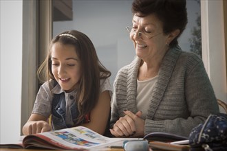 Older Hispanic woman reading with granddaughter