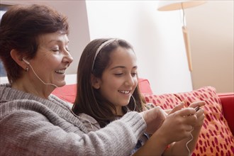 Older Hispanic woman listening to music with granddaughter