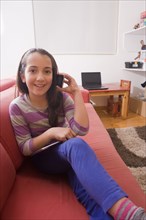 Hispanic girl talking on cell phone on sofa