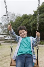 Hispanic boy playing on swing