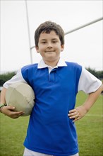 Hispanic boy holding rugby ball on field