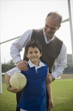 Hispanic man smiling with son on field