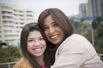 Hispanic mother and daughter smiling outdoors
