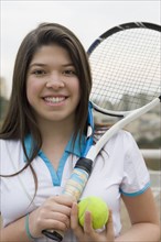 Hispanic girl playing tennis outdoors