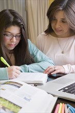 Hispanic mother helping daughter with homework