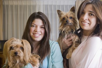 Hispanic mother and daughter holding dogs