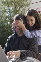 Hispanic girl covering father's eyes
