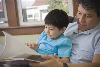 Hispanic father reading to son