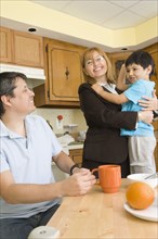 Hispanic mother hugging son in kitchen